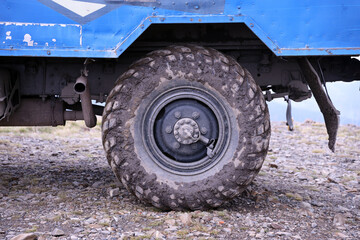 Fototapeta na wymiar Wheel closeup in a countryside landscape with a mud road. Off-road 4x4 suv automobile with ditry body after drive in muddy road area