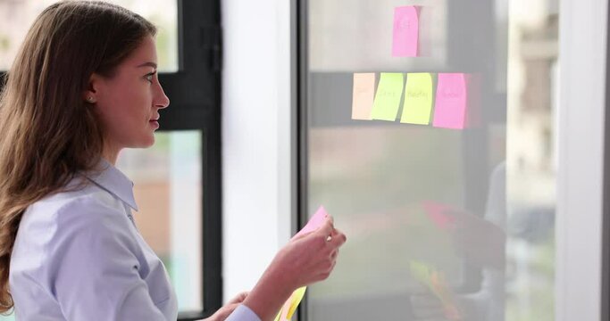 SEO manager or mentor gluing colored stickers on glass in office