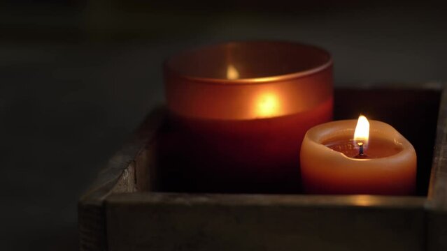 Pair of brown candles burning on dark background. 4K video