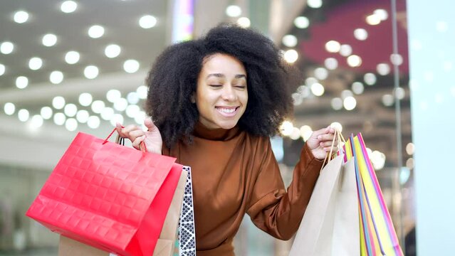 Portrait happy glad young woman shopper shopping in mall after sales and discount looking at camera joyful smiling shows colorful gift bags with purchases satisfied contented content buyer lady indoor