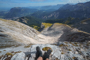 Ein Wanderer steht mit seinen Bergstiefeln am Abgrund und Blickt in das Oberkar an der Alpsitze...