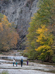 Obraz premium family walking inside gorge at Taughannock Falls State Park, a tourist destination in the Finger Lakes region of upstate New York. Famous waterfall in autumn with leaves changing color, foliage.