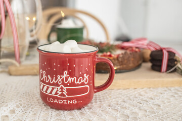 red Christmas mug with cocoa and marshmallows. on the table with Christmas cake. Christmas. New Year. cozy home