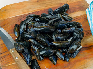 tas de moules crues, en gros plan, sur une planche à découper