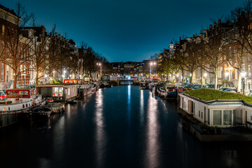 Fototapeta premium Captivating Night in Amsterdam: A Mesmerizing Long Exposure Photo of Amsterdam's Nighttime Canals.