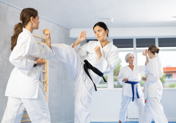 Karate lessons in the gym - women in pairs train punches and kicks