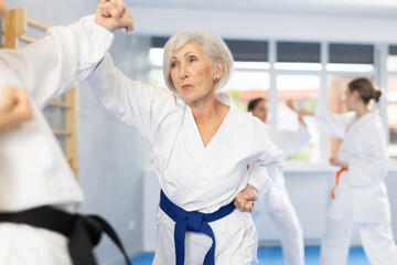 Fototapeta premium Young girl and woman during martial arts karate class train to perform basic blows to opponent with their hands and feet. Preparation of athletes for competitions