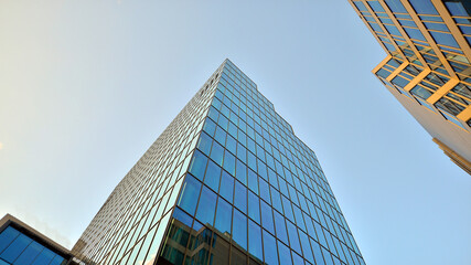 Looking up blue modern office building. The glass windows of building with  aluminum framework.