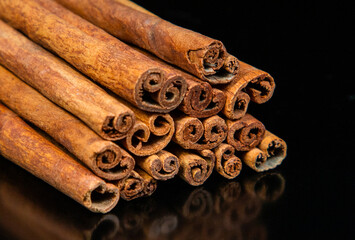 A close-up with a pile of cinnamon sticks on a black background