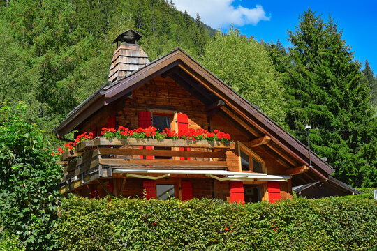 Traditional wooden alpine chalet with geranium flowers on the window in summer