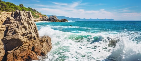 The beautiful blue sea waves crashed against the rocks creating a picturesque landscape on the beach in Italy making it the perfect summer vacation destination for nature loving travelers
