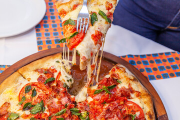 Taking slice of pizza top view close up with melted cheese
