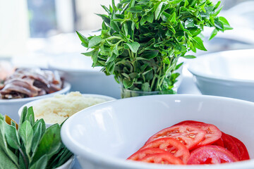 Pizza restaurant bench with pizza ingredients basil tomatoes, onions close up with window background