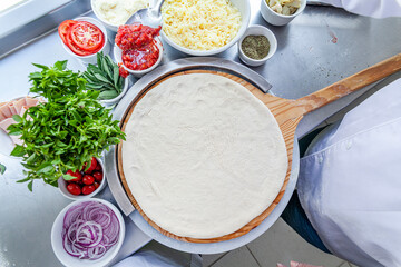 Making pizza bench top view spreading pizza dough