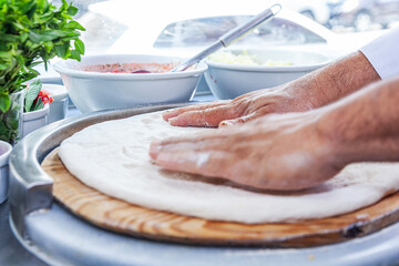 Man chef hand making craft pizza top view spreading pizza dough