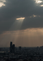 The sun's rays passing through the clouds and illuminate skhining down over the skyscraper of bangkok. Hole lighting selecting.