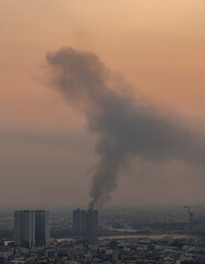 Plume of black smoke clouds from Burnt buildings on fire at some area in the bangkok city in the evening. Fire disaster accident, Selective focus.