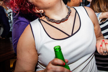 Woman dancing at the night club holding a beer close up