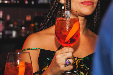 Woman with braids holding a drink at a club close up