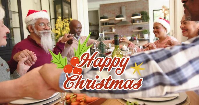 Animation of happy christmas text over diverse senior friends saying graces at christmas dinner