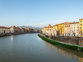 Fototapeta premium Idyllic riverside view featuring a tranquil body of water surrounded by buildings in Parma, Italy.