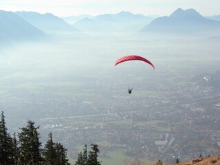 Paraglider soaring in the sky over the town and mountains.
