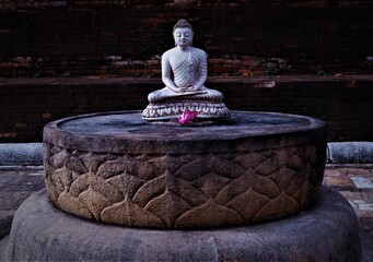 Closeup of the Buddha statue seated on a stone pedestal in lotus position