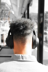 Male with a modern haircut wearing headphones in the public bus
