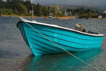 Naklejka na ściany i meble Blue boat peacefully floating in the lake in spring