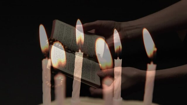 Composite video of burning candles against woman hands holding bible and rosary praying