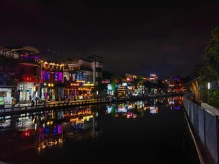 many shops are lit up at night on the water canal