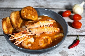 shrimp and bread in soup with tomatoes, chili and garlic