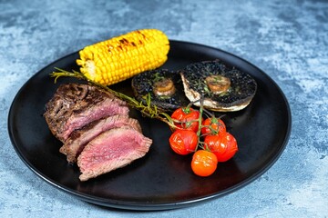 Juicy grilled steak served with fresh tomatoes and corn