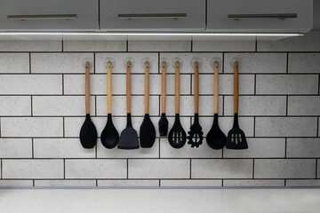 Closeup of a collection of silicon kitchenware hanging on a wall - obrazy, fototapety, plakaty