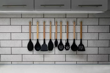 Foto op Canvas Closeup of a collection of silicon kitchenware hanging on a wall © Wirestock