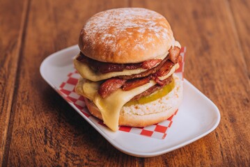 Closeup shot of an appetizing burger with bacon and cheese on a white plate.