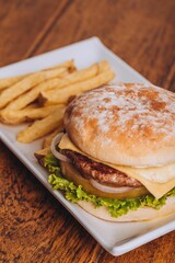 Closeup shot of a delicious hamburger with French fries on a wooden table.