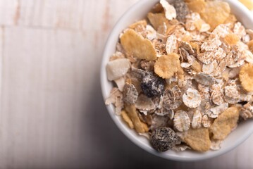 Aerial shot of dry oatmeal in a white bowl on a wooden surface