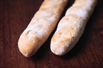 Freshly-baked bread resting on a wooden table top, with a light dusting of flour