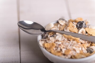 Close-up shot of a spoon and dry oatmeal in a white ceramic bowl