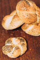 four rolls of bread with poppy sprinkles sit on a wooden cutting board