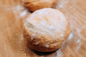 Single freshly-baked bread roll on a wooden background, lightly dusted with flour