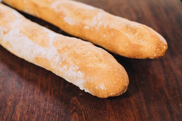Pair of freshly-baked baguettes resting on a rustic wooden table