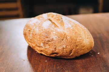 Freshly-baked bread resting on a wooden table top, with a light dusting of flour