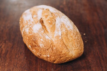 Freshly-baked bread resting on a wooden table top, with a light dusting of flour