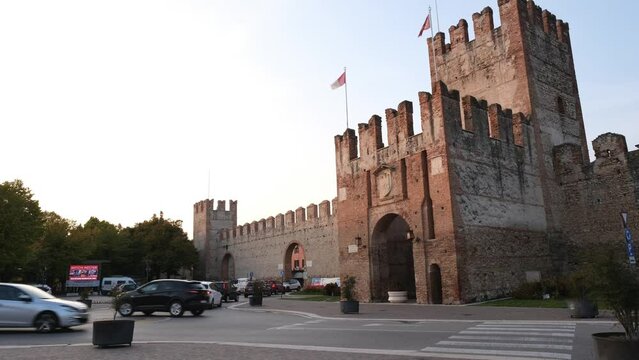 Time lapse footage of the movement of people and cars around the gateway and city walls of Soave