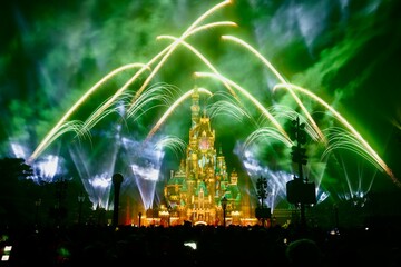 fireworks shooting up into the air with a castle lit in green