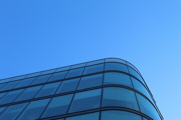 Low-angle shot of a modern blue glass skyscraper against the blue sky
