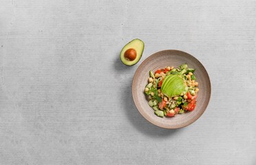 Top view of a bowl of avocado salad on a gray background