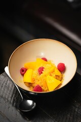 Vertical of a dessert with mango and raspberries